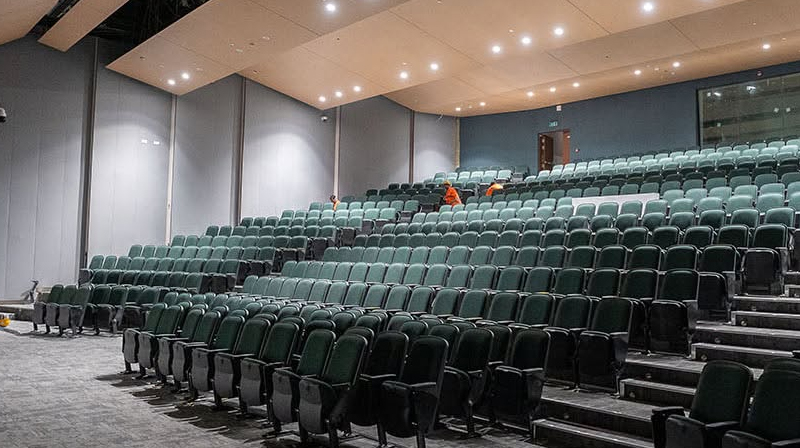Interior view of the 650-seat theatre auditorium at American Community School Abu Dhabi, located on Saadiyat Island, UAE. Drama by Design provided specialist theatre and audio visual consultancy for the new campus, working alongside architects AECOM. The auditorium incorporates LED stage lighting, fixed lighting bars, an overhead technical gantry, professional sound reinforcement, projection facilities and an induction loop assisted listening system. The project was completed in March 2024.