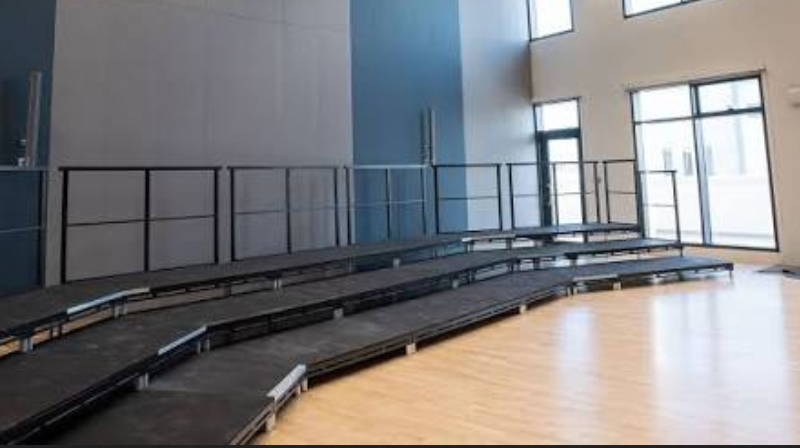 Portable modular staging arranged within the drama studio at American Community School Abu Dhabi, providing a flexible performance platform.